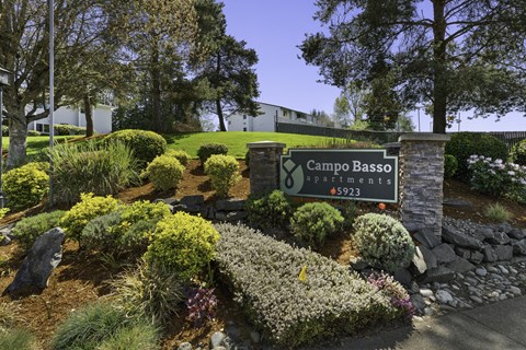 Campo Basso Property Sign with Lush Plants, Shrubs, and Bushes Under at Campo Basso Apartment Homes, Lynnwood, Washington 98087